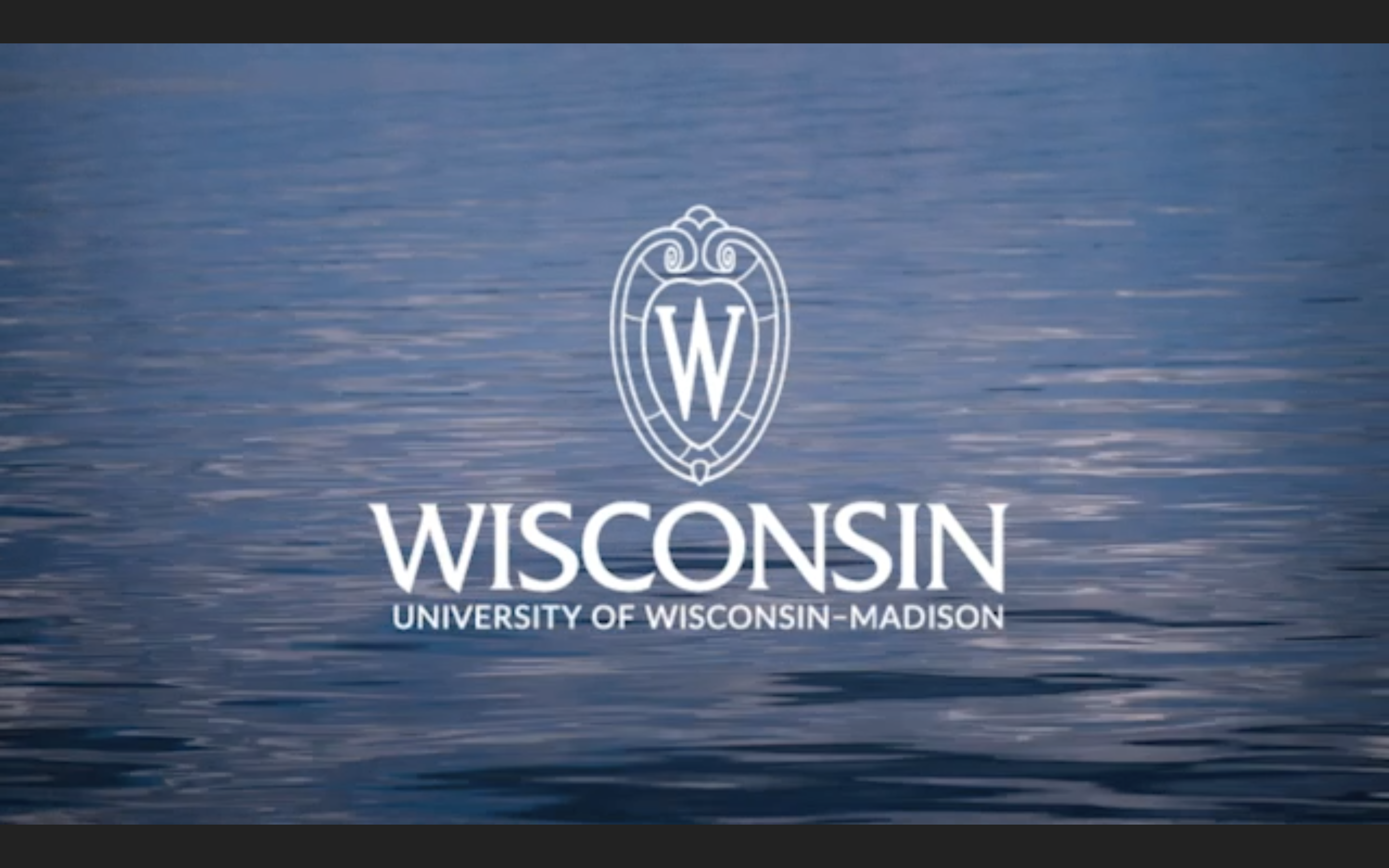 Video still of the white outline UW–Madison logo over an image of water ripples on the surface of Lake Mendota