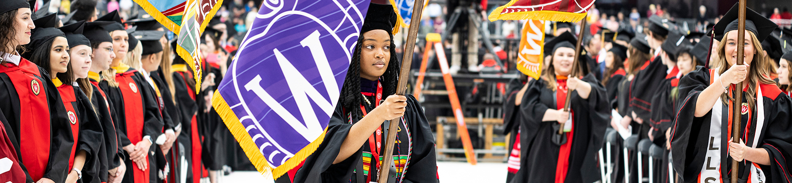 Flag bearers lead the academic procession during UW–Madison's spring commencement ceremony at the Camp Randall Stadium