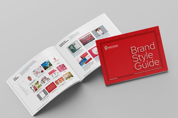 Photo of an open brand booklet showing colorful images in a grid layout. A closed version of a red covered booklet lies partially on top of the opened pages.