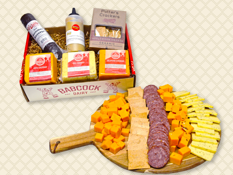 A Babcock Dairy Cheese Gift Box with three cheeses, crackers, summer sausage and beer mustard, along with a display of cheeses and sausage.