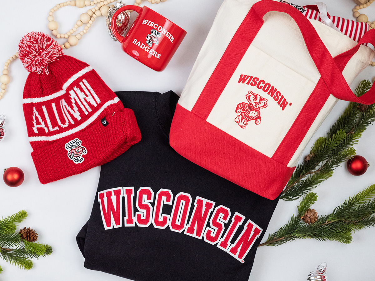 Some of the items available from the UW Alumni Store - a red Alumni beanie hat, a red Wisconsin Badgers mug, a white and red Wisconsin canvas tote bag and a Wisconsin sweatshirt.