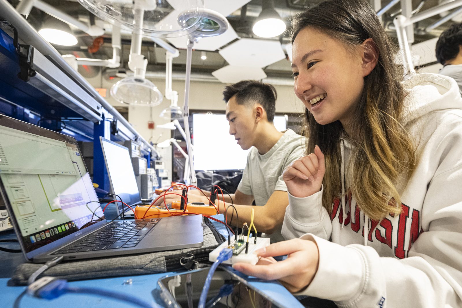 Two students working with circuit breadboards attached to laptops.