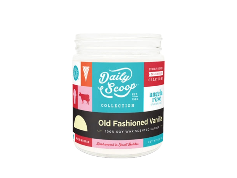 A white jar candle labeled 'Daily Scoop Collection Old Fashioned Vanilla' with colorful graphics including an ice cream cone, cow silhouette, and terrace chair, indicating it is a 100% soy wax scented candle hand-poured in small batches.