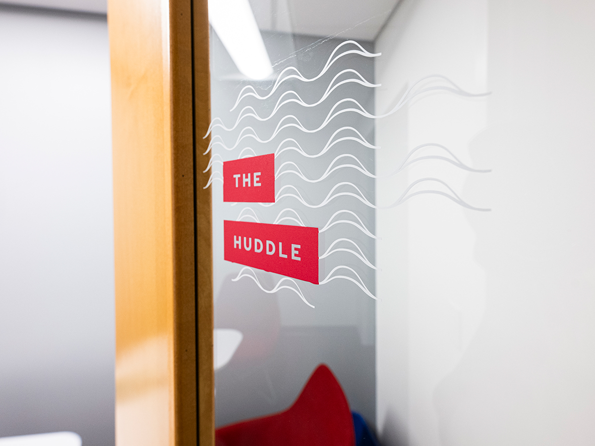 Vinyl label reading "The Huddle" on a glass door to a conference room