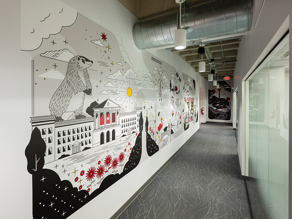 After photo of a long corridor with a detailed mural featuring a large badger and Bascom Hall.