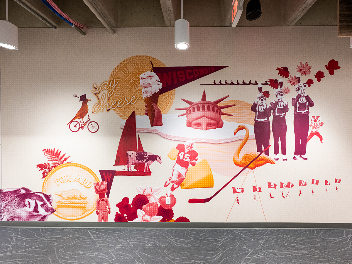 After photo of a large-scale photo illustration on an office wall. The illustration features UW–Madison iconic imagery: ice cream, the band, hockey stick, flamingo yard sign, Lady Liberty, cheese, a football player, Bucky Badger, and flowers.