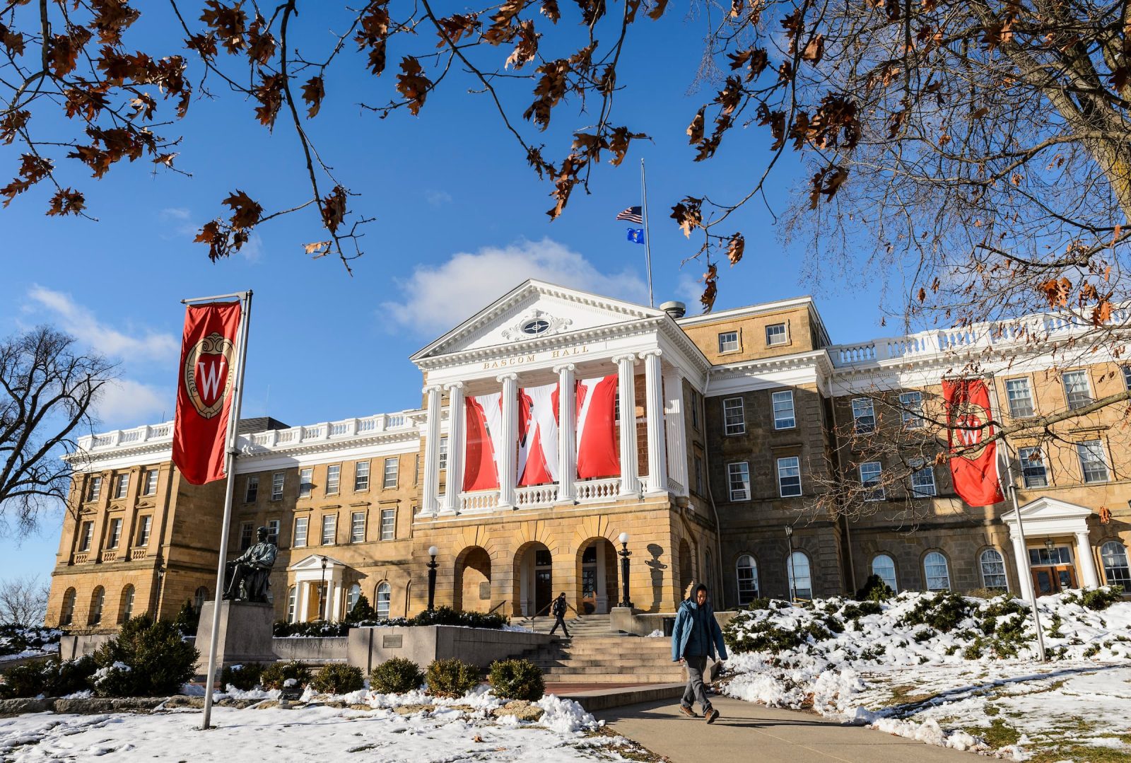 Bascom Hall in winter, with large red “W” banners hanging between the columns and snow covering the ground.